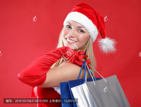 一個年輕迷人的女孩打扮成Santa與購物袋在他們手中的肖像