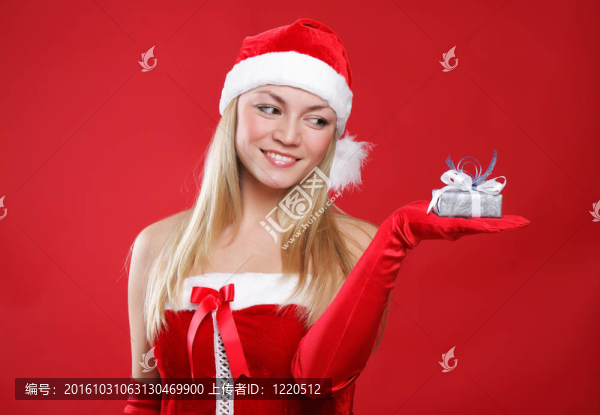 年輕漂亮的女孩裝扮成圣誕老人手里拿著一件小禮物。