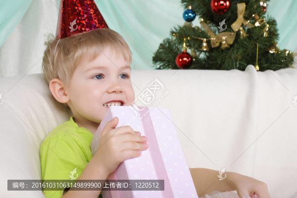 靠近圣誕樹的小男孩坐著禮物