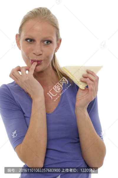 一個(gè)年輕的白人婦女用手指在嘴里吃三明治的肖像