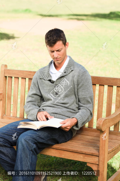 人在長凳上讀他的書