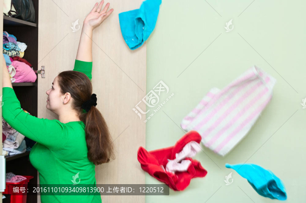 年輕白人婦女從衣柜后面扔衣服。
