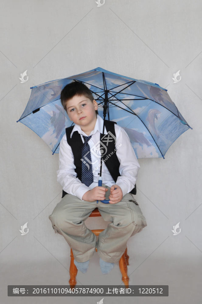 一個帶著雨傘的男孩坐在椅子上