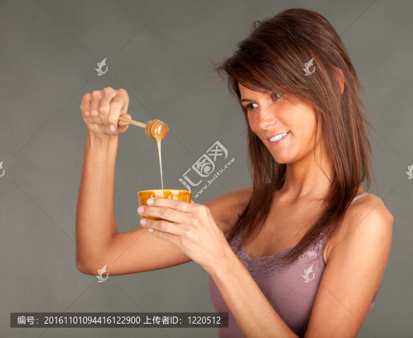 微笑的年輕女人，蜂蜜罐；灰色背景