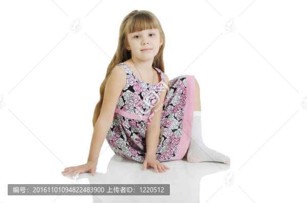 迷人的小女孩坐在地板上。在白色背景上隔離