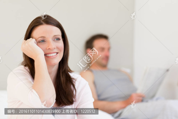 可愛(ài)的女人看著相機(jī)，而她的丈夫正在睡覺(jué)