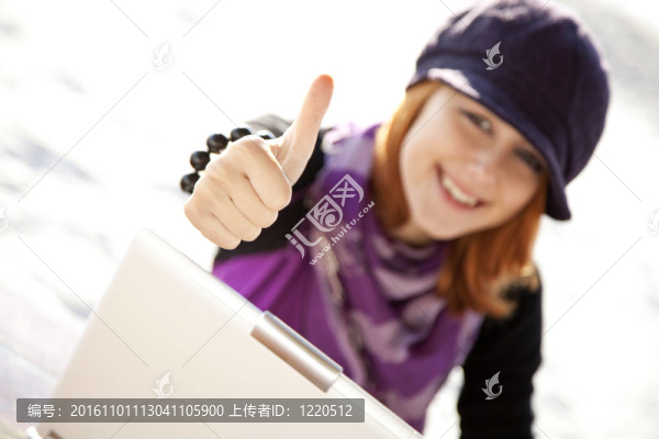 在海灘上與筆記本電腦的紅頭發(fā)女孩肖像。