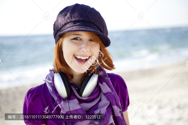 在海灘上帶著耳機(jī)的紅頭發(fā)女孩肖像。