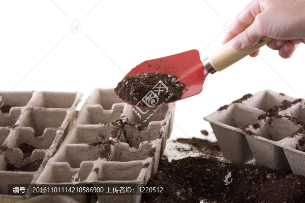 手用鏟子將土壤放入環(huán)保堆肥盆