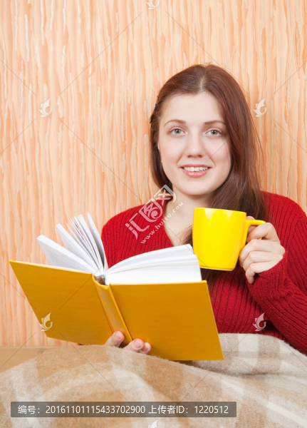 漂亮的年輕女孩在沙發(fā)上看書