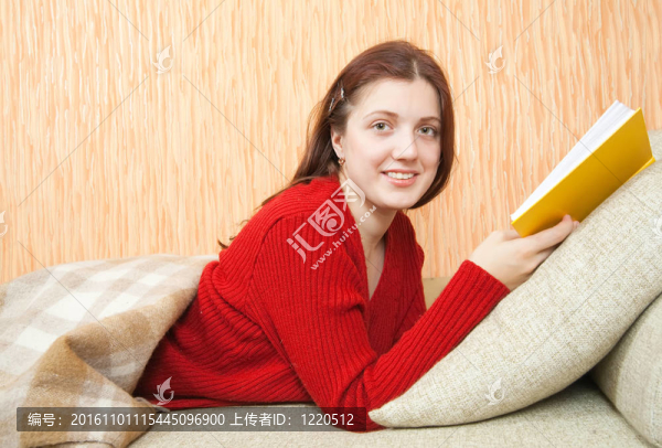 漂亮的年輕女孩在沙發(fā)上看書
