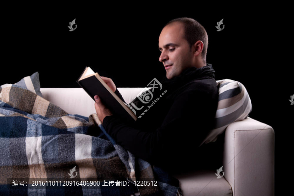 躺在沙發(fā)上看書(shū)的男人；被孤立的黑色；攝影棚。