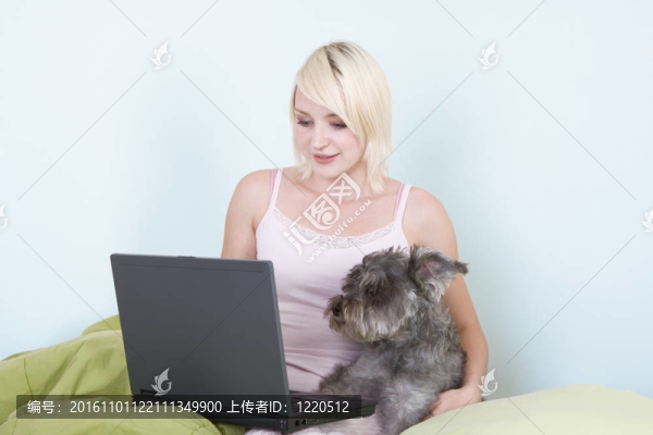 年輕的女人在床上用筆記本電腦和雪納瑞犬-匯圖網(wǎng) www.fosd68.com 年輕的女人在床上用筆記本電腦和雪納瑞犬