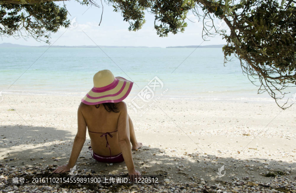 坐在海灘上戴著帽子的女人