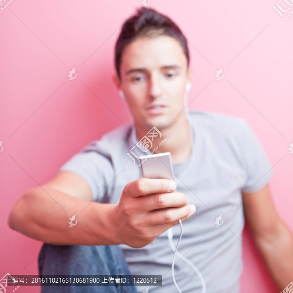 年輕英俊的男人在他的便攜式MP3播放器在自己的房間里聽音樂（顏色色調(diào)的圖像）