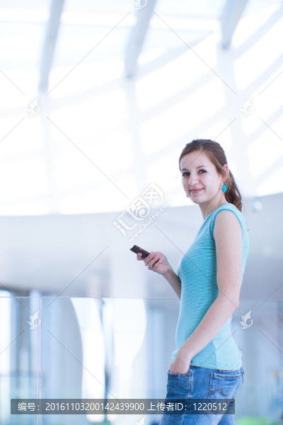 漂亮的年輕女人說她；使用移動電話/手機在公共區(qū)域（淺景深；顏色色調(diào)的圖像）