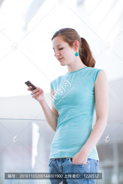 漂亮的年輕女人說(shuō)她；使用移動(dòng)電話/手機(jī)在公共區(qū)域（淺景深；顏色色調(diào)的圖像）