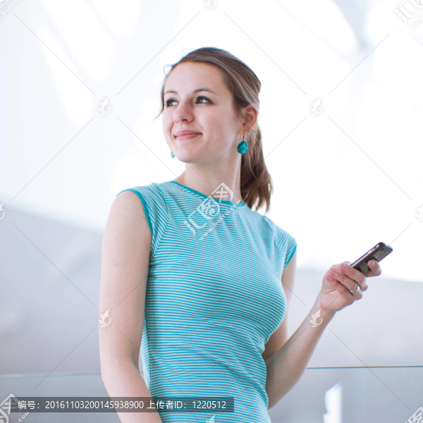 漂亮的年輕女人說(shuō)她；使用移動(dòng)電話(huà)/手機(jī)在公共區(qū)域（淺景深；顏色色調(diào)的圖像）
