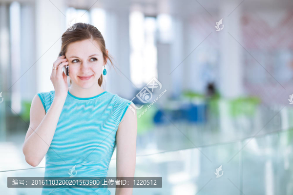 漂亮的年輕女人說她；使用移動電話/手機在公共區(qū)域（淺景深；顏色色調(diào)的圖像）