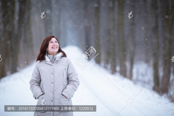享受著第一場雪：在一個可愛的森林路徑看雪花飄落的年輕女子（顏色色調的圖像）