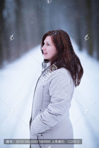 享受著第一場雪：在一個可愛的森林路徑看雪花飄落的年輕女子（顏色色調的圖像）