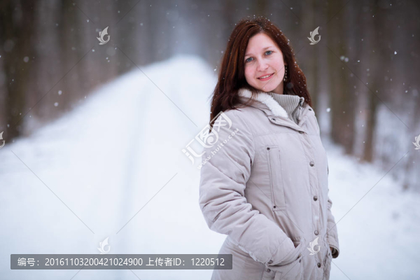 享受著第一場雪：在一個可愛的森林路徑看雪花飄落的年輕女子（顏色色調(diào)的圖像）