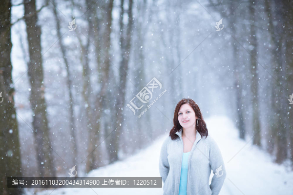 享受著第一場雪：在一個可愛的森林路徑看雪花飄落的年輕女子（顏色色調(diào)的圖像）