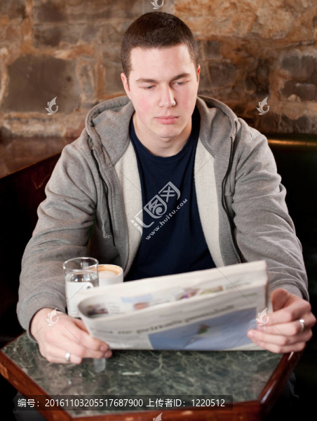 早上的咖啡和新聞-英俊的年輕人閱讀的報(bào)紙?jiān)贐AE和喝咖啡