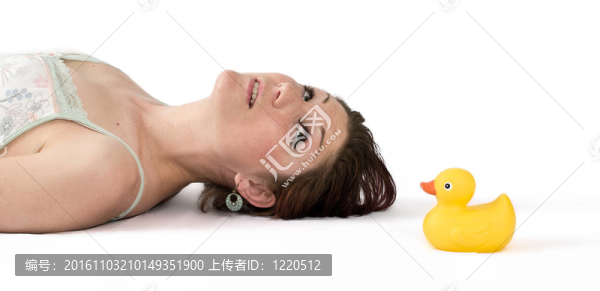 年輕女子躺在地板上看著橡皮鴨