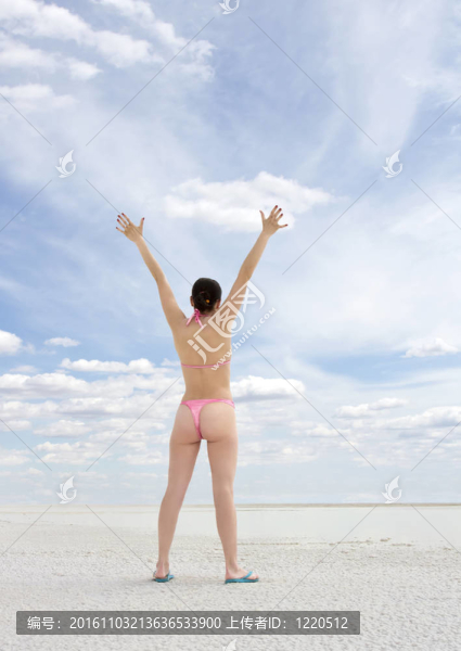 站在海灘上享受陽(yáng)光的年輕女子
