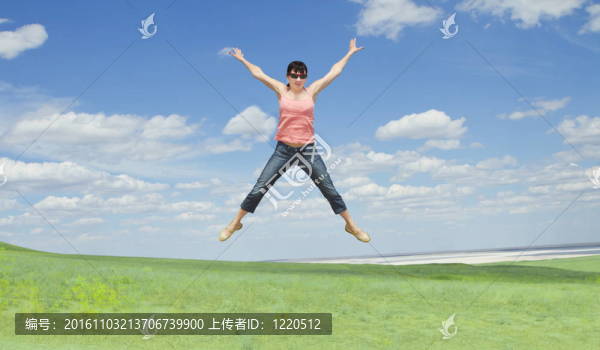 漂亮的年輕女子在碧綠的草地上跳上藍(lán)天