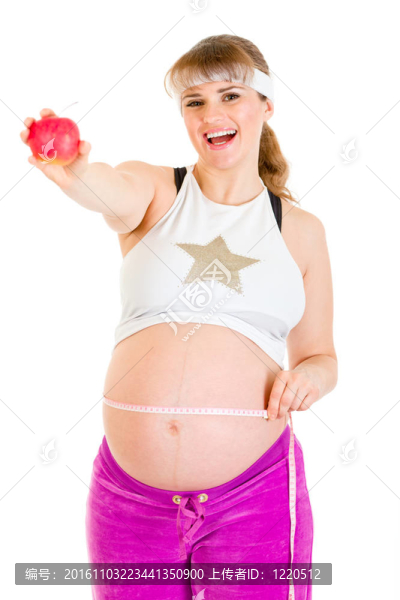 微笑美麗的孕婦測量她的腹部和控股蘋果孤立的白色