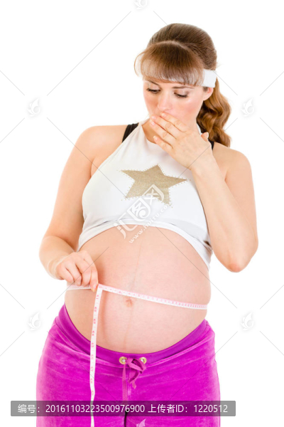 驚訝美麗的孕婦測量她的腹部孤立的白色