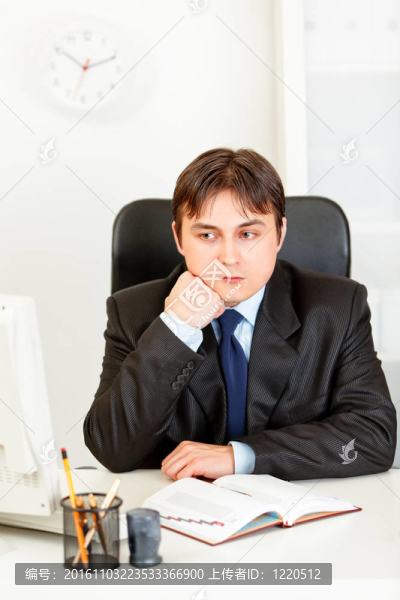沉思的商人的男人坐在辦公桌旁，保持頭部在手