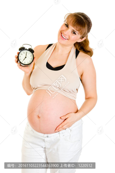 嬰兒的方式！微笑孕婦抱著鬧鐘孤立在白色