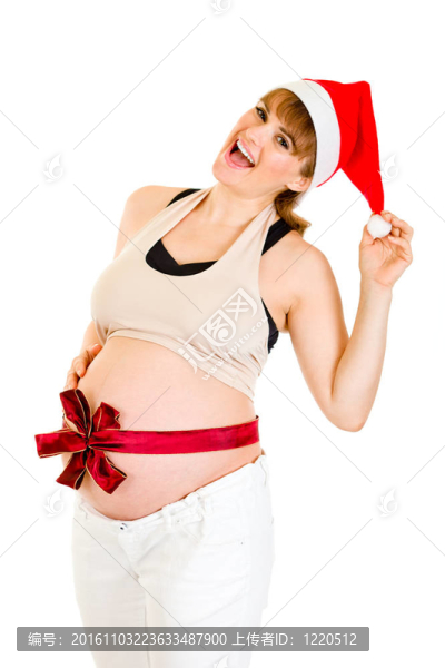 幸福美麗的孕婦在Santa帽子與紅絲帶對(duì)腹部孤立的白色