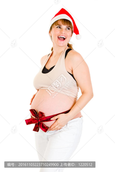 快樂(lè)圣誕孕婦在Santa帽子與紅絲帶對(duì)腹部孤立的白色