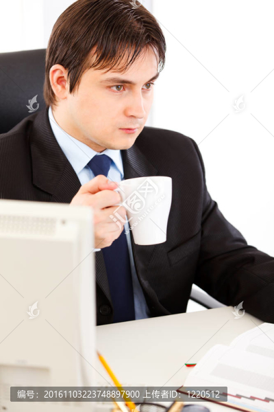 體貼的商人坐在辦公桌旁，手里拿著一杯茶