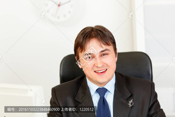 坐在辦公桌旁的微笑的現(xiàn)代商人