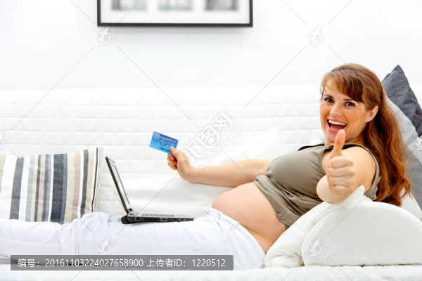微笑美麗孕婦使用信用卡購物從互聯(lián)網(wǎng)和顯示豎起手勢