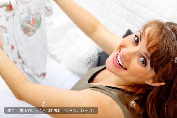 微笑美麗孕婦坐在沙發(fā)上與嬰兒衣服在手。特寫(xiě)。