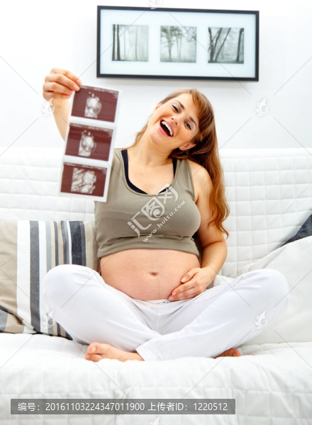 笑著美麗懷孕的女性坐在沙發(fā)上用手呼應(yīng)。