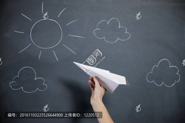 一只雌手準(zhǔn)備發(fā)射紙飛機(jī)。在背景天空和太陽的黑板