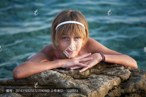 在海邊巖石上放松的少女