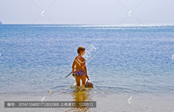 男孩在海灘上散步與椰子