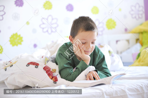 在他的床上的小男孩讀一本書