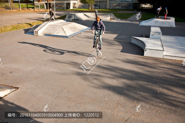 年輕的紅頭發(fā)的男孩是他的自行車在玩滑板公園跳