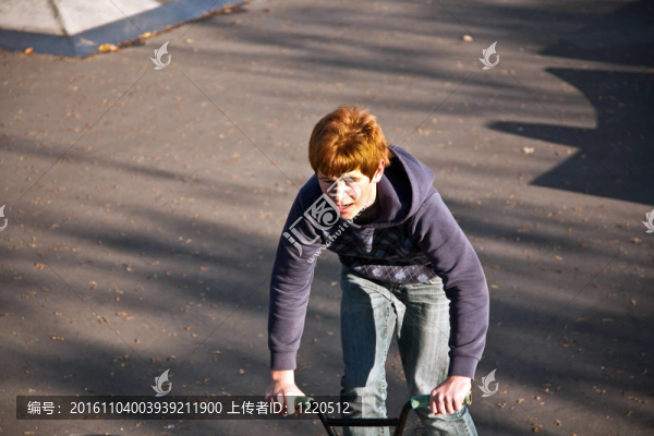 敬紅頭發(fā)的男孩是他的自行車在玩滑板公園跳
