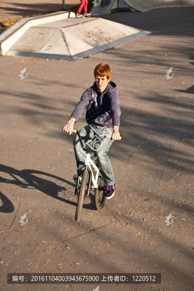 敬紅頭發(fā)的男孩是他的自行車在玩滑板公園跳
