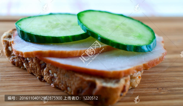 木板上有黃瓜和火腿三明治